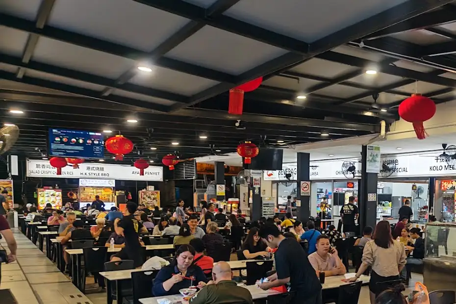 An evening at Great Food Emporium: diners at the tables and the hawker stalls lit up behind